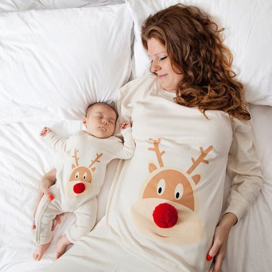 母親と子供がトナカイ柄のクリスマスパジャマを着てベッドに横たわっている