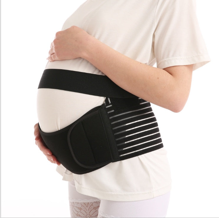 Pregnant woman wearing black maternity support belt holding belly